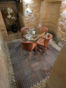 a glass table and chairs on a stone patio at Sand - Rooftop Views, Wine Cellar & Espresso in Senglea