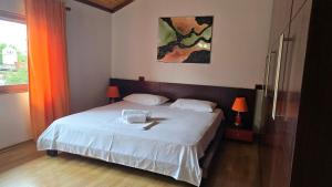 莱什Eni's Villa, 5km From Shengjini Beach的一间卧室配有一张带白色床单和绘画的床。
