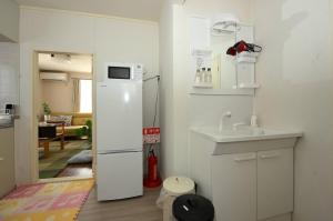 Una cocina con un refrigerador blanco y un fregadero. en StayChacha 城下町茶茶1F2F 一棟貸切, en Marugame