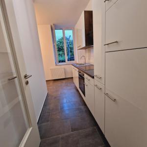 a kitchen with white cabinets and a tile floor at Heart of Essen in Essen