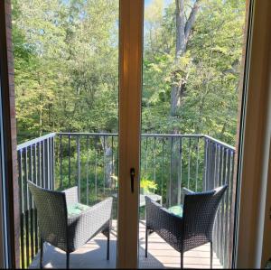 a balcony with three chairs and a window at Green Apartament Chill Modlin Airport in Kazuń Nowy