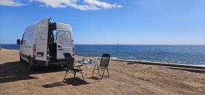 a van parked on the beach with a table and chairs at Van Master in Puerto del Rosario