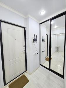 a bathroom with a white door and a mirror at Уютная квартира в хорошей точке города in Taraz