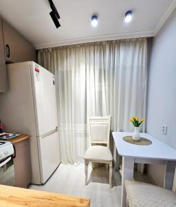 a kitchen with a white refrigerator and a table and chairs at Уютная квартира в хорошей точке города in Taraz