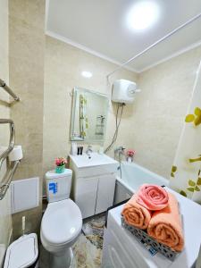 a bathroom with a toilet and a sink and a tub at Уютная квартира в хорошей точке города in Taraz