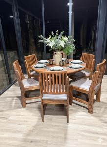 a wooden table with four chairs and a vase with flowers at Pozas y Cascadas La Presa in Río Cuarto