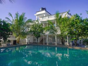 a swimming pool in front of a house with palm trees at Escape Hole in Diani Beach