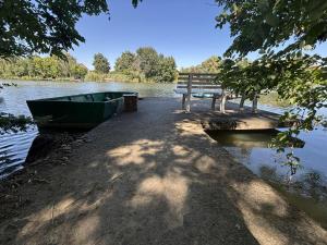 a bench and a boat next to a lake at Peresi paradicsom in Mezőtúr