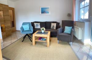 a living room with a couch and two chairs and a table at Dünenhaus mit Schwimmbadnutzung in Göhren
