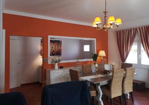 a dining room with orange walls and a table and chairs at Family Villa Pool & Beach in Caparica