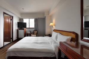 a hotel room with a large bed and a television at Moonlight Hotel in Hsinchu City