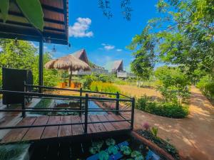 a wooden deck with a pond in a garden at Private Pool Sun Shade Resort & Spa in Habarana
