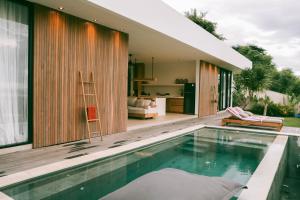 a house with a swimming pool and a living room at Yemaya Villas in Kuta Lombok