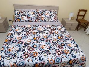 a bed with a floral comforter and two pillows at La Fenice in Mola di Bari