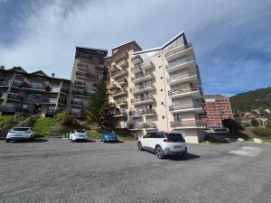 a parking lot with cars parked in front of a building at Studio cabine Les Angles - Soleil et Montagne in Les Angles