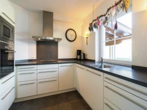 a kitchen with white cabinets and a clock on the wall at Holiday Home Brixen near Skiwelt Slopes in Brixen im Thale