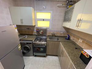 a small kitchen with a stove and a sink at Modern Comforts Await! Spacious 2BR 2Bath w Free WiFi Stylish Furniture in Madinaty