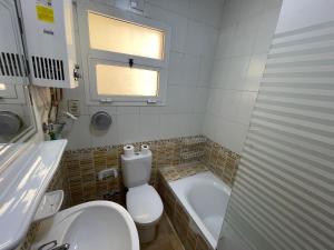a bathroom with a toilet and a tub and a sink at Modern Comforts Await! Spacious 2BR 2Bath w Free WiFi Stylish Furniture in Madinaty +6 photos