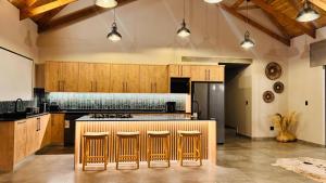 a kitchen with wooden cabinets and a kitchen island with bar stools at 19 on Idwala, Mabalingwe Game Reserve in Warmbaths