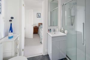 a white bathroom with a shower and a sink at Serendipity - Sweet home with sweeping sea views in Isle of Wight