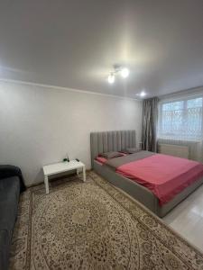 Un dormitorio con una cama grande y una mesa. en Квартира, en Pavlodar