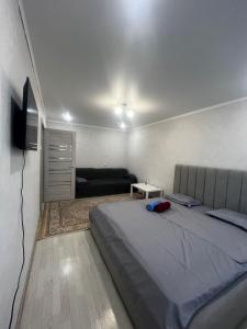 Un dormitorio con una cama y un televisor de pantalla plana. en Квартира, en Pavlodar
