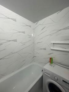 Un baño blanco con bañera y lavadora. en Квартира, en Pavlodar