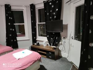 a bedroom with a bed and a tv and windows at Sussex Lodge Contractors House in Slough +7 photos