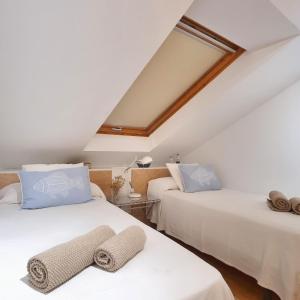 two beds with towels on them in a attic room at Marusía Home, playa Langosteira in Fisterra