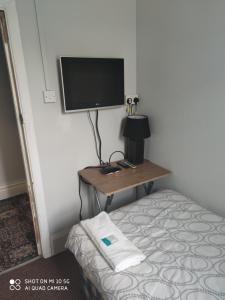a room with a bed and a television on a wall at Sussex Lodge Contractors House in Slough