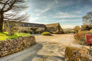 ein Steinhaus mit einer Steinmauer und einer Straße in der Unterkunft Nadin Cottage in Buxton