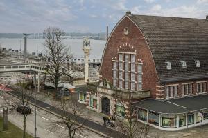a large brick building with a clock tower next to a river at Hostel am Hafen Kiel in Kiel