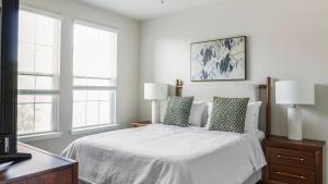a bedroom with a bed with two lamps and two windows at Landing Apartments - Sereno in Wimauma +39 photos