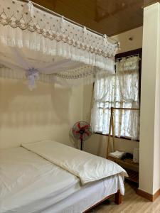 a bedroom with a white bed and a window at A Tứng House Bản Giốc in Trùng Khánh