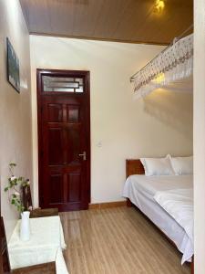 a bedroom with a bed and a wooden door at A Tứng House Bản Giốc in Trùng Khánh