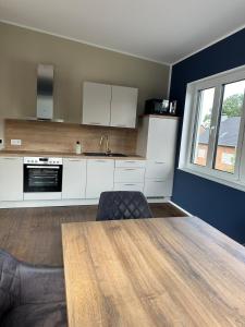 a kitchen with white cabinets and a wooden table at Neubau FeWo in Haltern am See in Haltern +3 photos