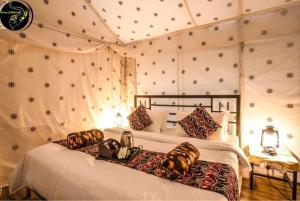 una camera da letto con due letti in una stanza con le pareti innevate di Dunes Heritage Desert Camp a Jaisalmer