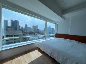 Schlafzimmer mit einem großen Fenster mit Stadtblick in der Unterkunft Fanhua Life IN Nanjing West Road Store 1 in Shanghai