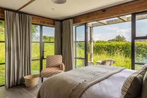 a bedroom with a bed and a chair and windows at Louma Country Hotel in Wootton Fitzpaine