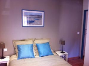 a bedroom with a bed with two blue pillows at La Maison de Noémie in Leucate