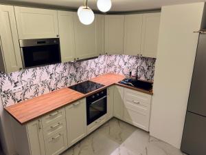 a kitchen with white cabinets and a wooden counter top at Apartament - Mieszkanie, nocleg przy Centrum Zdrowia Dziecka - Warszawa Międzylesie Wawer - Dzięcieliny 15 in Warsaw +2 photos