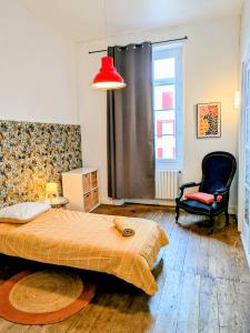 a bedroom with a bed and a chair and a red lamp at White Chapel in Condom