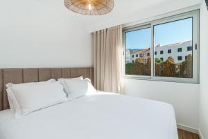a bedroom with a white bed and a window at Star Lit Jacuzzi Apartment in Câmara de Lobos +19 photos