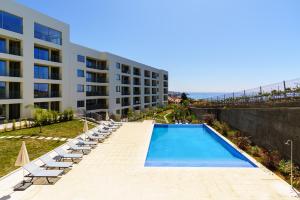 a swimming pool with lounge chairs and a building at Star Lit Jacuzzi Apartment in Câmara de Lobos
