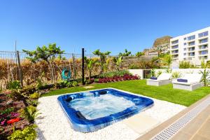a backyard with a hot tub in the grass at Star Lit Jacuzzi Apartment in Câmara de Lobos