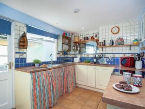 eine Küche mit blau und weiß gefliesten Wänden in der Unterkunft Port View Cottage in Shaldon + 20 Fotos