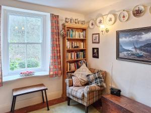 soggiorno con sedia e libreria di Carreg Yr Eos - Cottage a Fishguard Altre 33 foto