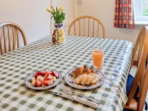una tavola con piatti di cibo e un bicchiere di succo d'arancia di Carreg Yr Eos - Cottage a Fishguard