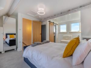 ein Schlafzimmer mit einem großen weißen Bett mit gelben Kissen in der Unterkunft Coastal Cottage in Norwich