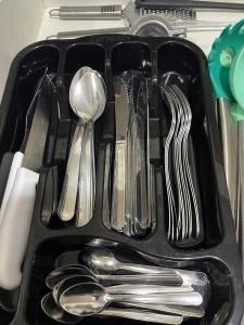 a black tray with spoons and forks and spoons at Quarto compartilhado 8 leitos Valor por pessoa in Aracaju